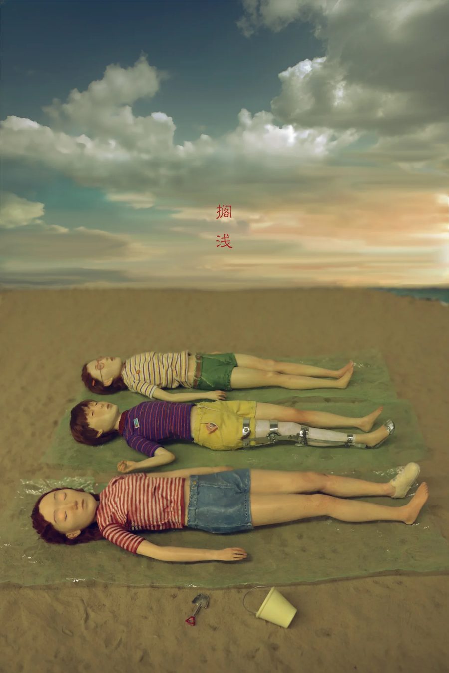 Three figures lying motionless on a beach beneath a cloudy s, 2021